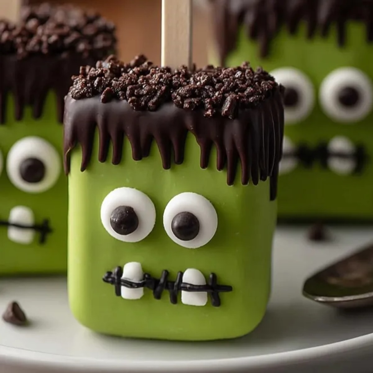 Close-up of spooky green Frankenstein Marshmallow Pops; semi-sweet chocolate hair detail.
