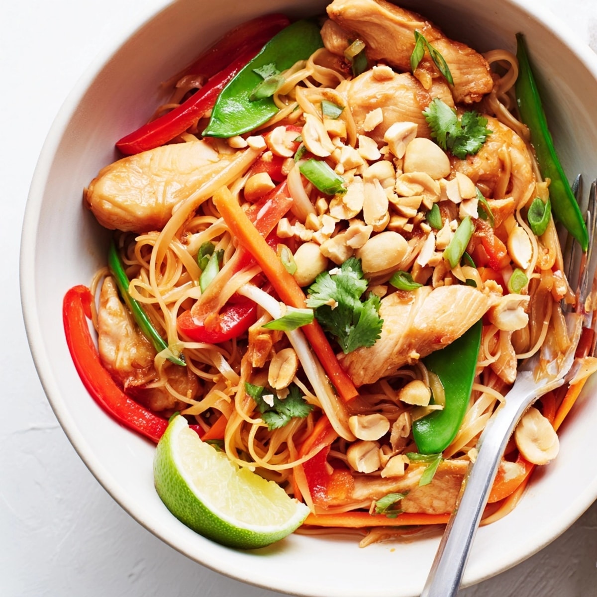 Close-up of glossy Thai Chili Chicken Noodle Bowls topped with colorful, fresh garnishes.