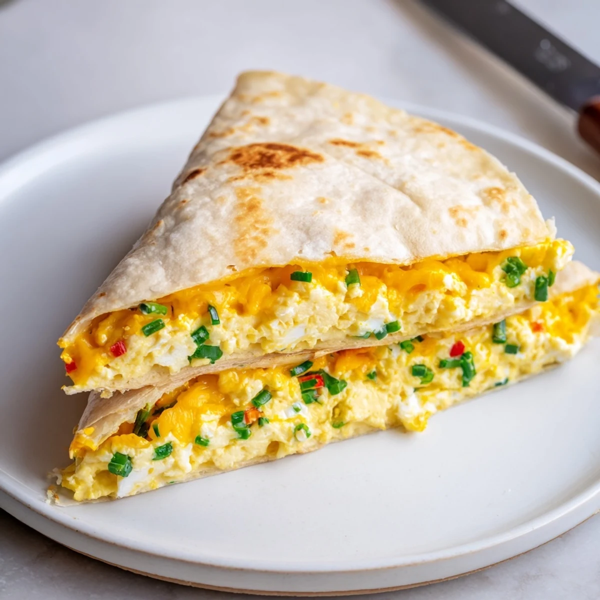 Creamy ricotta cheddar breakfast quesadilla paired with fresh herbs and scrambled eggs.  