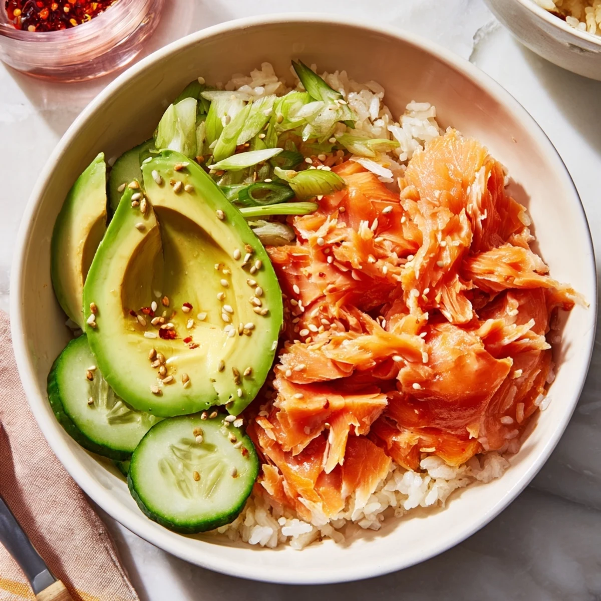 Bowl of leftover salmon and rice topped with fresh avocado and cucumber slices.  