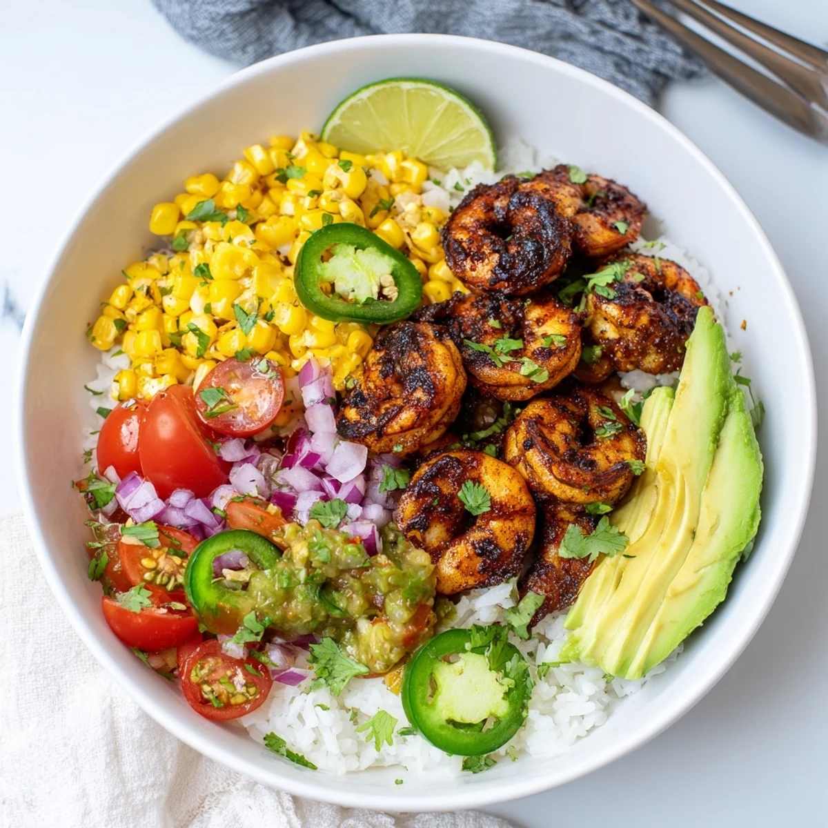 Colorful blackened shrimp bowl with fresh avocado corn salsa and lime for zest.  