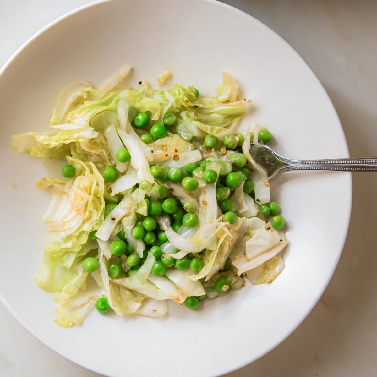 Vibrant plate of cabbage stir-fry, glistening from sesame oil, showcasing tender vegetables and savory sauce.