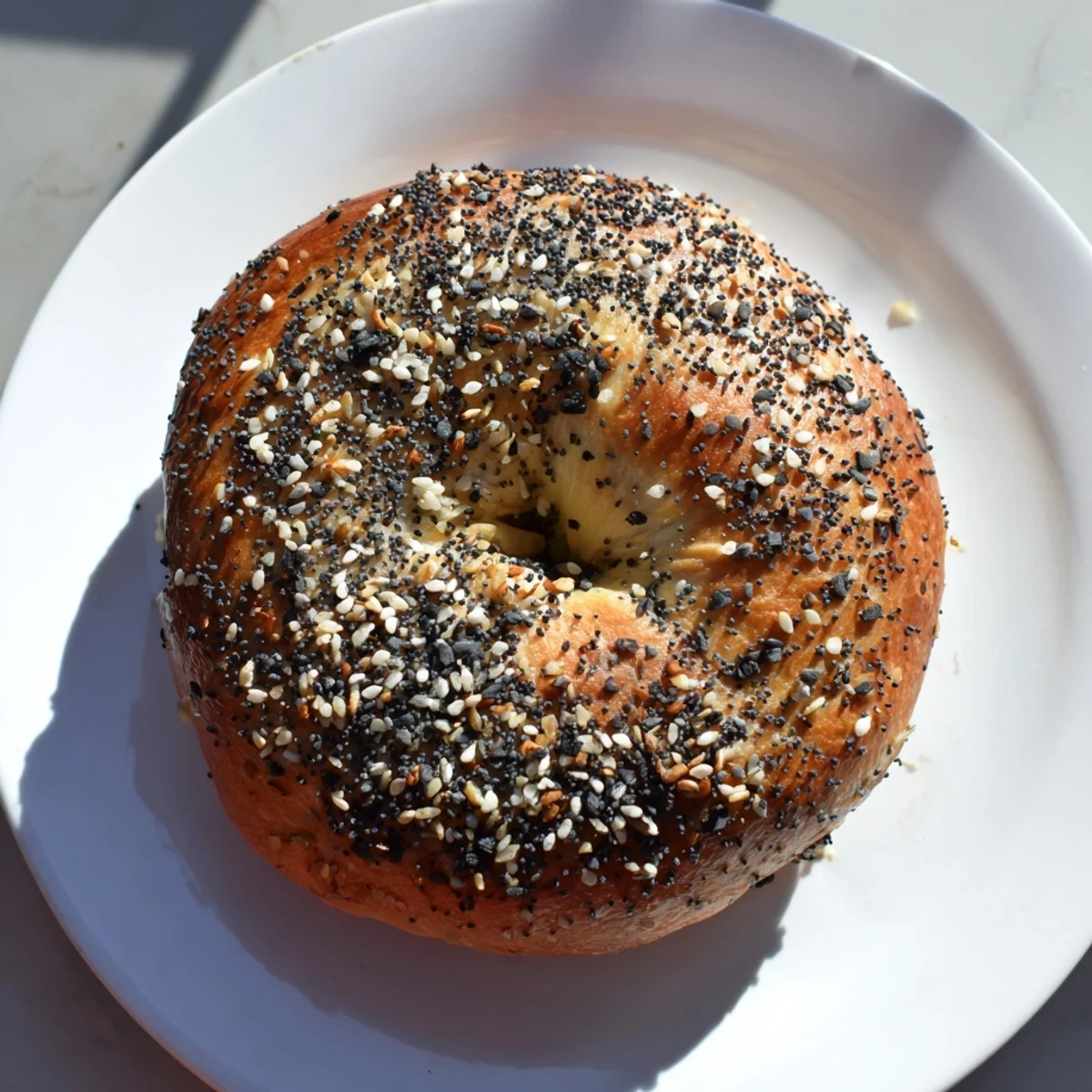 A close-up of beautifully baked Homemade Budget Bagels shows a sprinkling of sesame seeds, perfect for toasting.