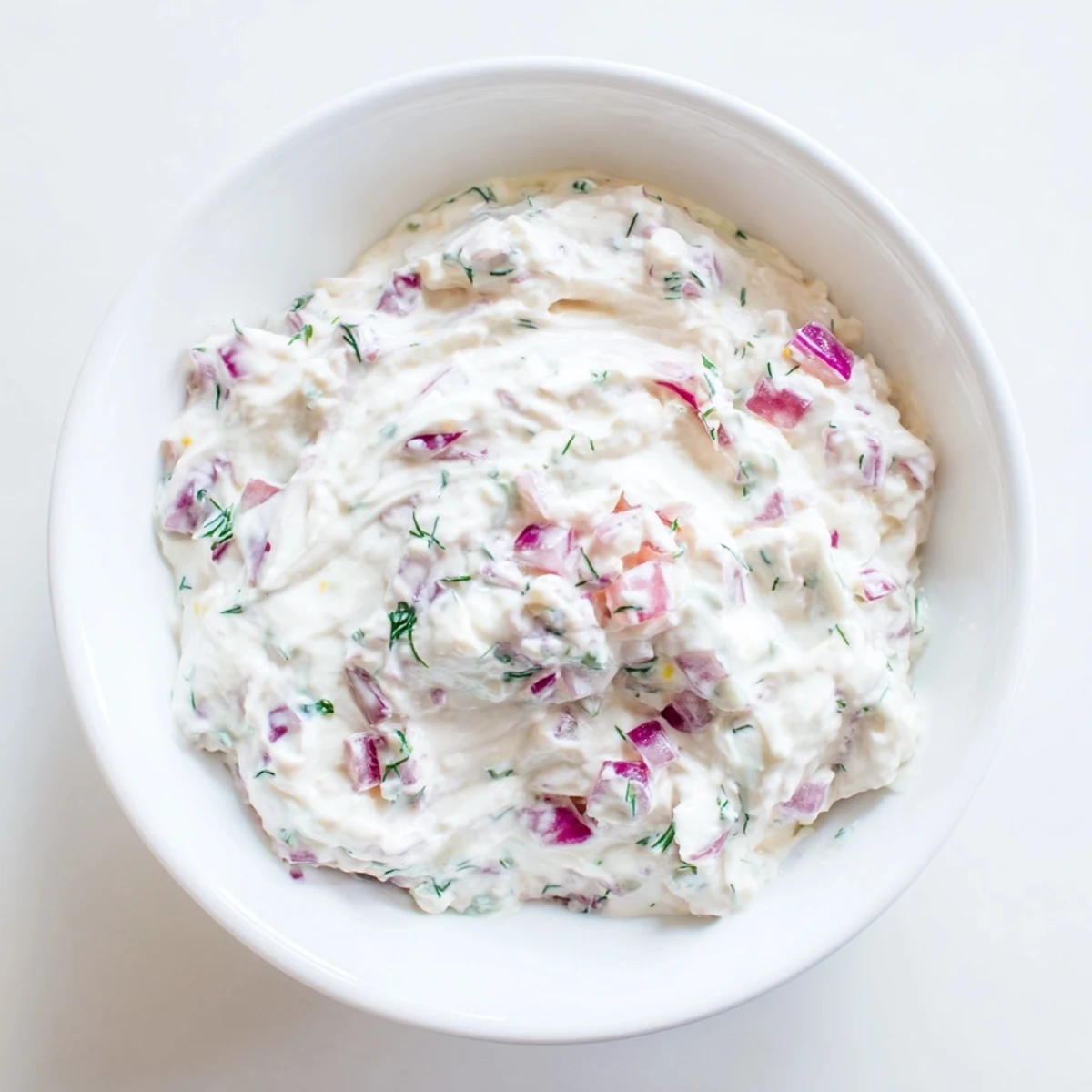 A close-up of a bowl of Sweet and Sour Pickle Relish Dip with fresh dill, ready to eat.
