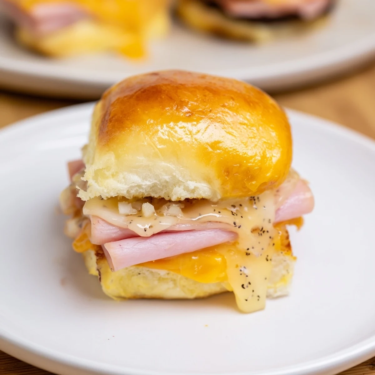 Golden-brown Baked Ham and Cheese Party Sliders, with melted Swiss and a buttery, savory glaze dripping down.