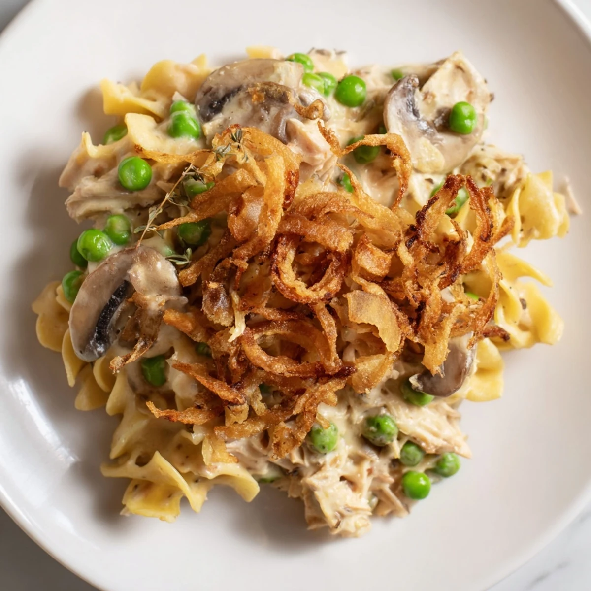 A creamy, savory homemade tuna noodle casserole is topped with a generous layer of crispy fried onions.
