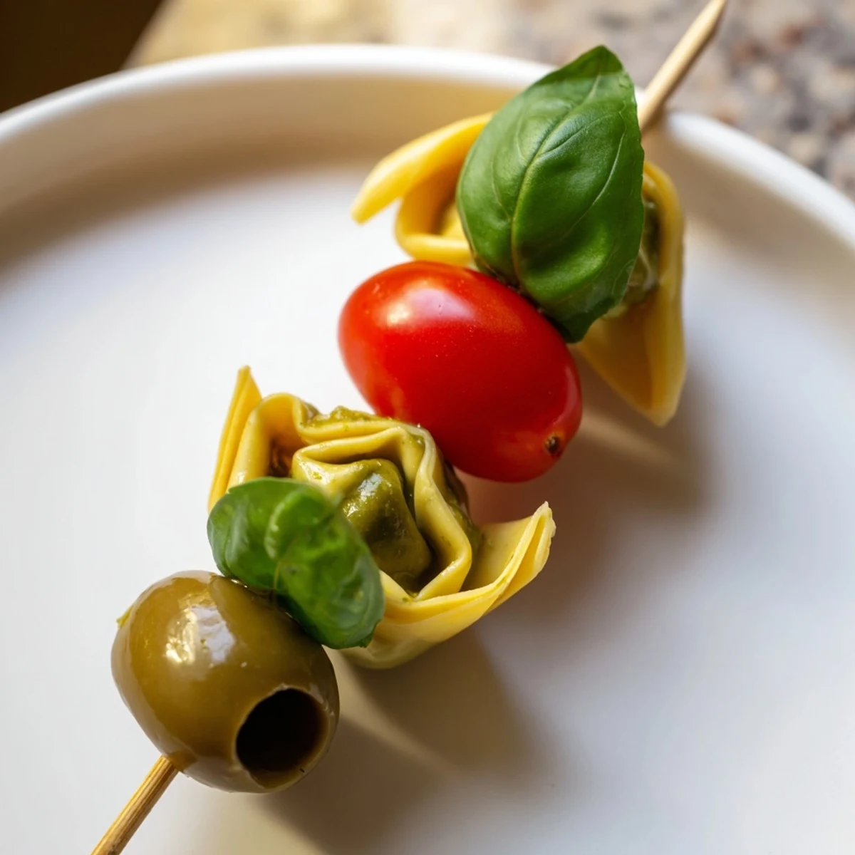 Appetizer Skewers: colorful tortellini, juicy tomatoes, and olives drizzled with aromatic pesto, ready to serve.