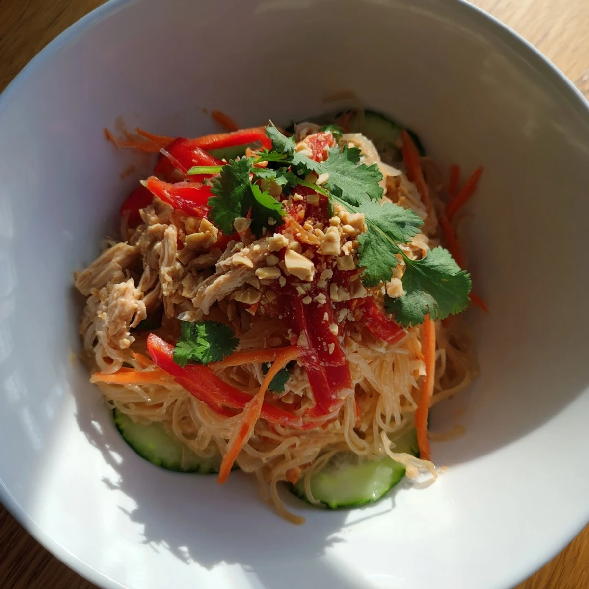 Close-up view of Thai-inspired peanut chicken pasta; creamy dressing, noodles, and juicy chicken.