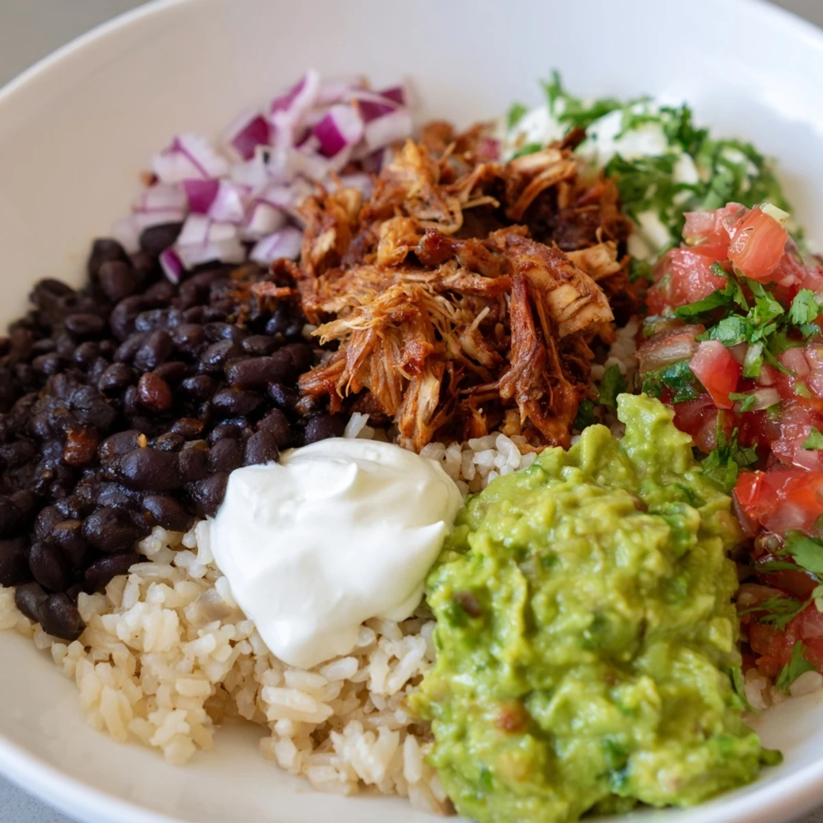 A loaded Chipotle Burrito Bowl copycat showcases tender carnitas, creamy queso, fresh salsa, and avocado.