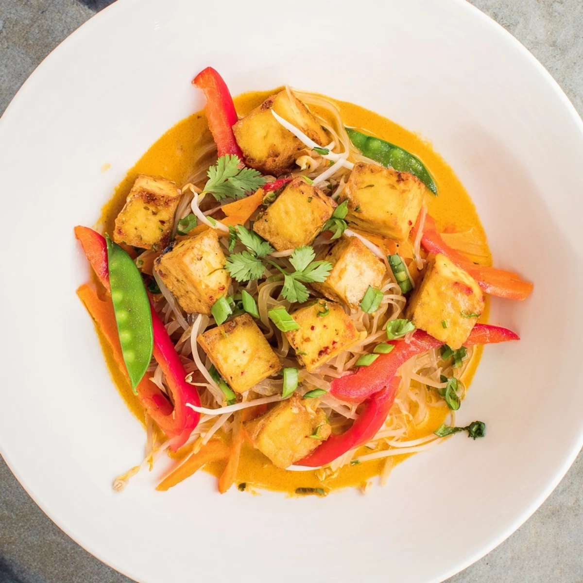 Steaming bowl of Malaysian Laksa Curry, featuring vibrant noodles, vegetables, and creamy broth.