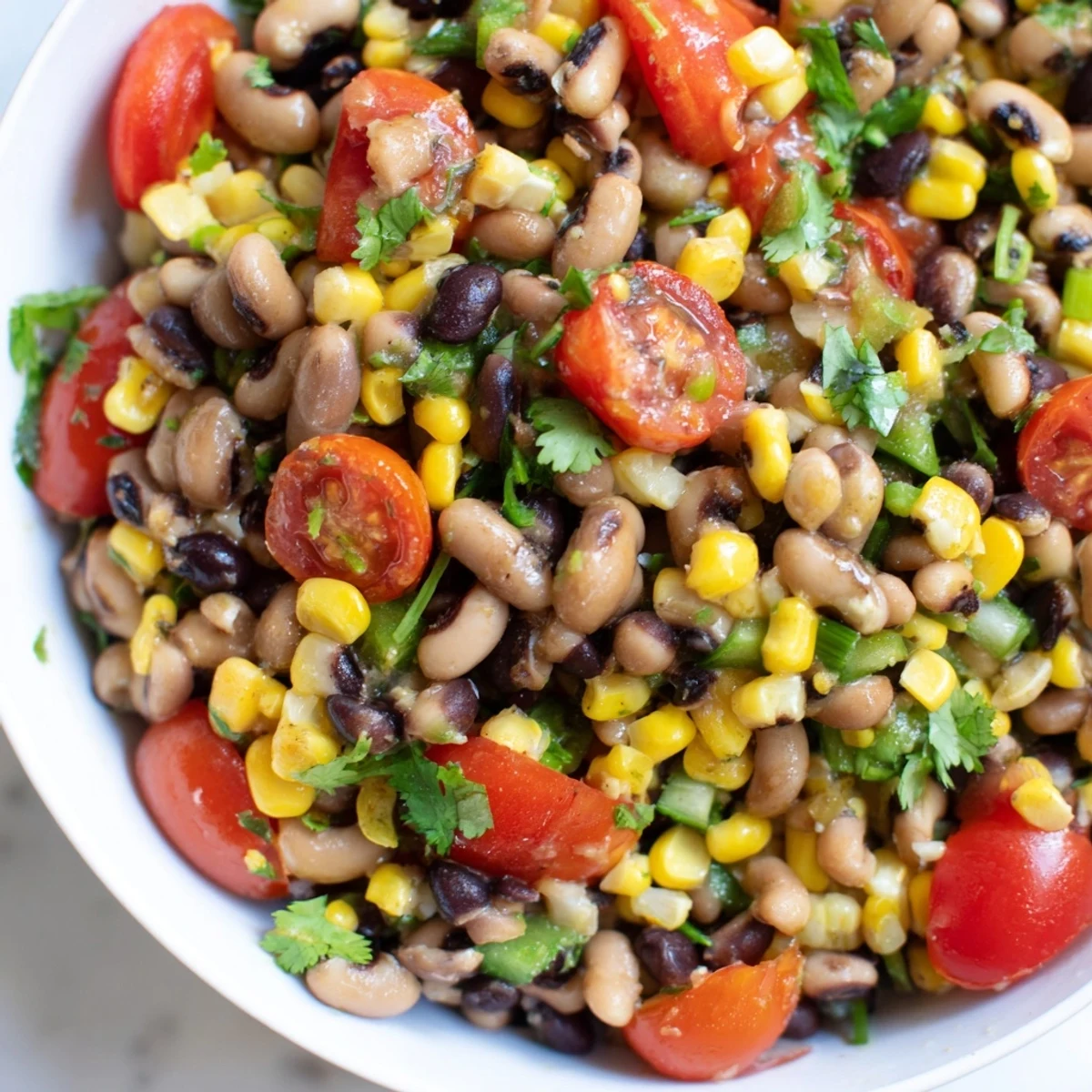 A chilled bowl of Cowboy Caviar, featuring black-eyed peas and jalapeños, ready for dipping with crisp tortilla chips.