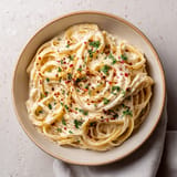 A bowl of pasta with red peppers and cheese.