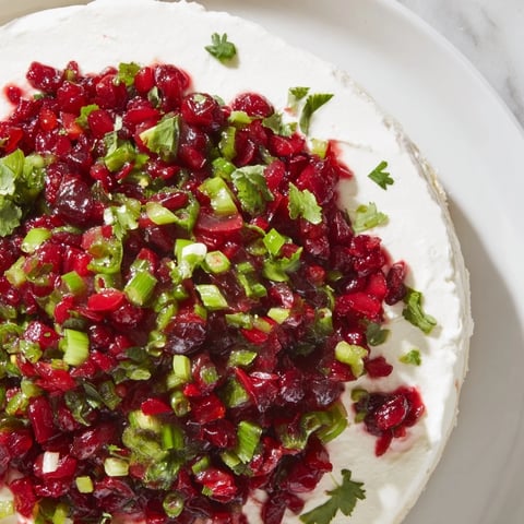 Spiced Cranberry Jalapeño Cream Cheese Dip: A festive appetizer featuring a luscious creamy base and vibrant toppings.