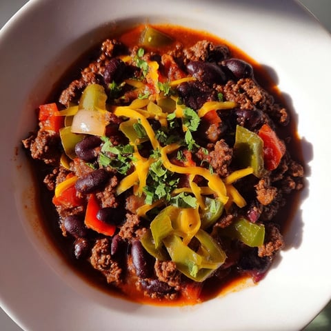 A steaming bowl of quick chili with canned beans, garnished with fresh cilantro and cheese.