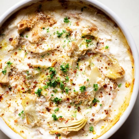 Warm, bubbling baked artichoke dip, a creamy appetizer perfectly served with crackers for dipping.