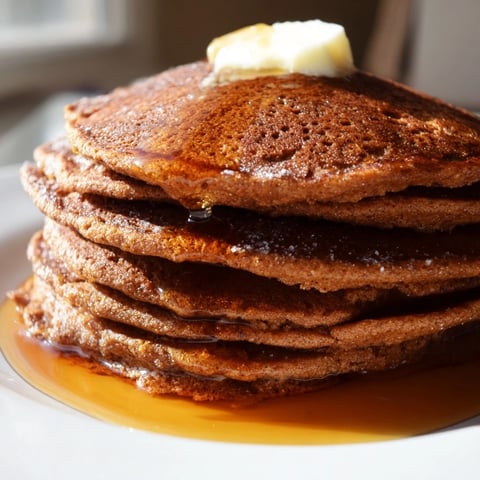 Golden brown Gingerbread Pancakes stacked high, ready to be drizzled with warm maple syrup.