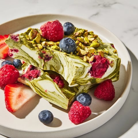 Creamy Frozen Yogurt Bark swirled with vibrant berries and pistachios, a delightful frozen treat suggestion.