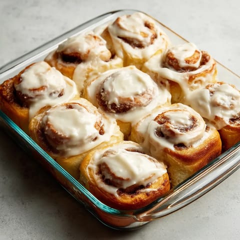 A glass dish filled with cinnamon rolls.