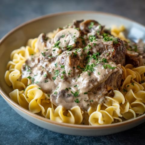 A bowl of pasta with mushrooms and meat.