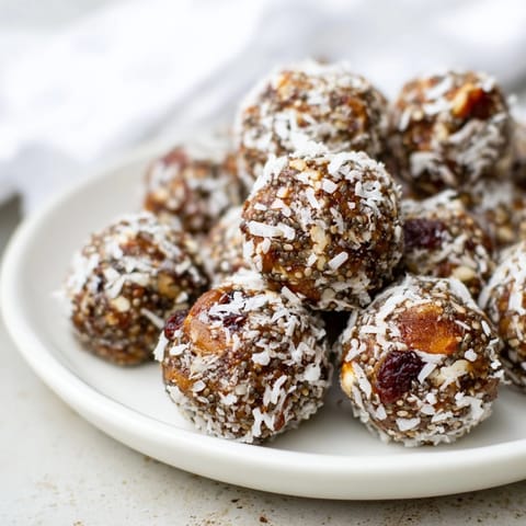 Spiced Holiday Snack Energy Balls rolled in coconut, ready to enjoy with warm cider.