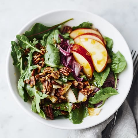 Vibrant salad featuring fresh greens, sliced apple, and crunchy roasted nuts.  
