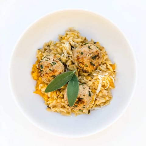 Glistening sage turkey meatballs nestled with bright orange pumpkin orzo, a fall favorite recipe idea.