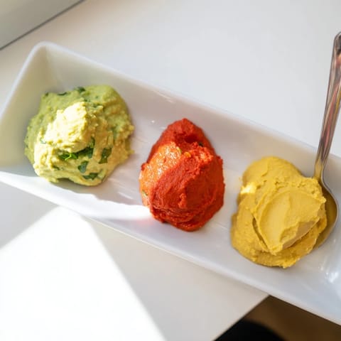 Imagine the Dip Trio: a delicious appetizer featuring avocado, pepper, and hummus, served with fresh vegetables.