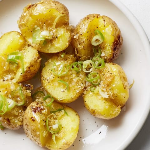 Oven-roasted Smashed Green Onion Potato Bombs, served hot with flaky sea salt, are a savory, golden-brown appetizer idea.