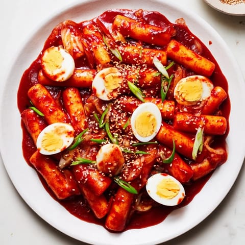 Spicy Korean tteokbokki: a close-up shows the rich, gochujang sauce coating the tender rice cakes.