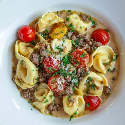 Creamy, rich Tortellini Beef Soup garnished with Parmesan and fresh herbs; a warming meal.
