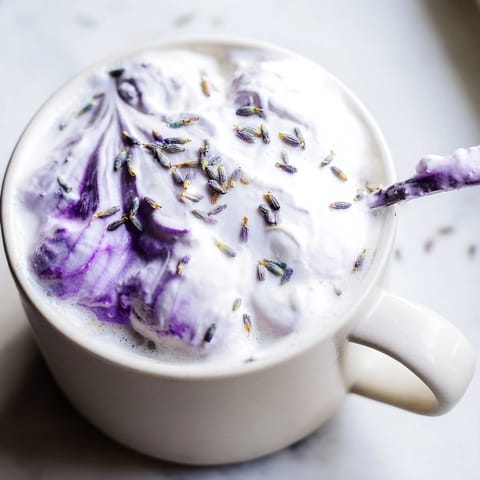 Velvety Whipped Lavender Latte showcases a creamy, purple-hued foam over a rich coffee drink.
