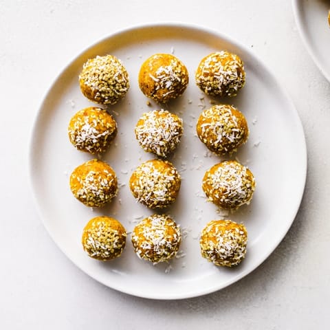 A close-up of vibrant Ginger Turmeric Energy balls, showcasing their textured surface with visible hemp seeds and oats.  