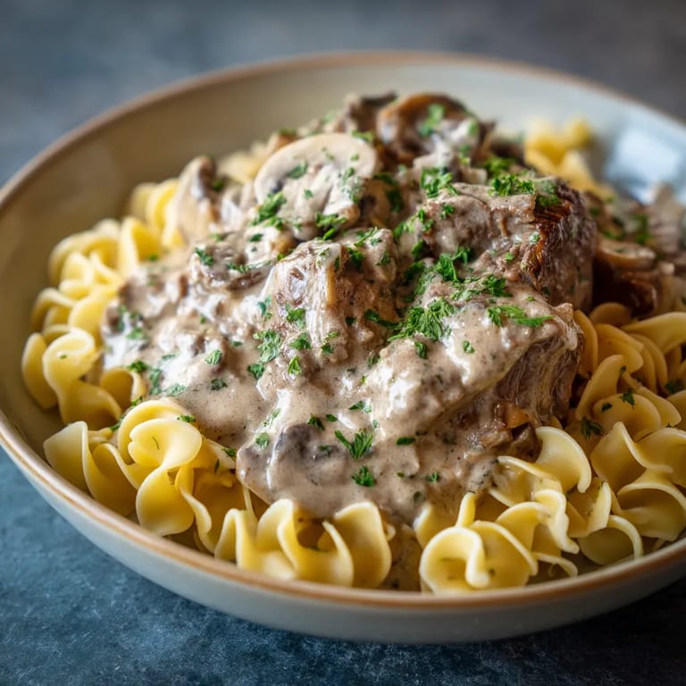 A bowl of pasta with mushrooms and meat.