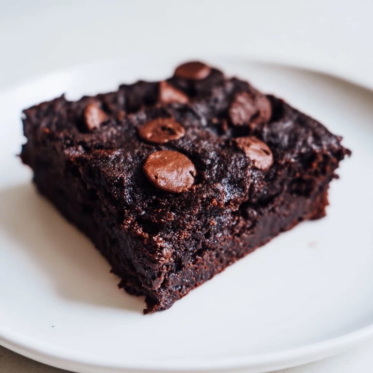 A square of rich, dark Black Bean Brownies, ready to eat, creating the perfect chocolatey treat.