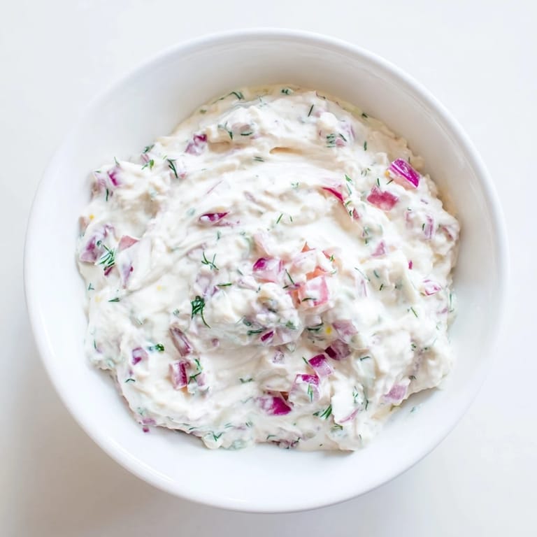 A close-up of a bowl of Sweet and Sour Pickle Relish Dip with fresh dill, ready to eat.