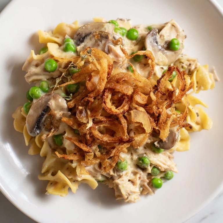 A creamy, savory homemade tuna noodle casserole is topped with a generous layer of crispy fried onions.