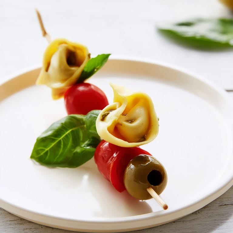 Delicious appetizer skewers featuring tortellini, pesto-covered and threaded alongside olives, perfect for a party.