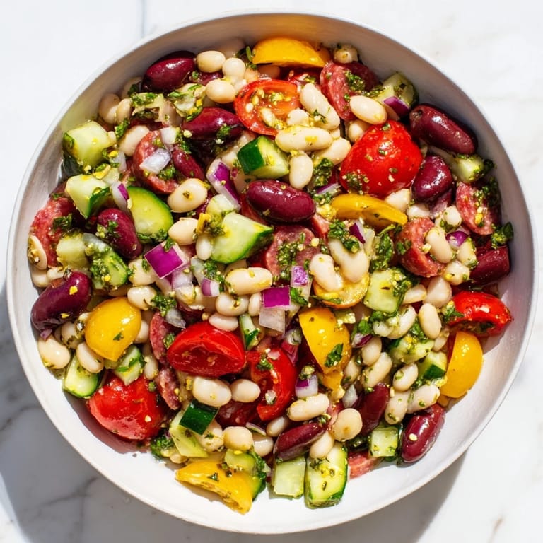 Delicious Mediterranean Dense Bean Salad with salami: a close-up of the flavorful, colorful ingredients after tossing.