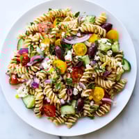 A vibrant bowl of lemon pasta salad, featuring fresh vegetables and creamy feta cheese.